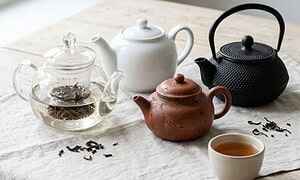 Negy teaskanna egymas mellett: uveg szurovel, feher porcelan, mazatlan agyag es ontottvas